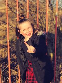 Portrait of cheerful girl gesturing while standing against railing