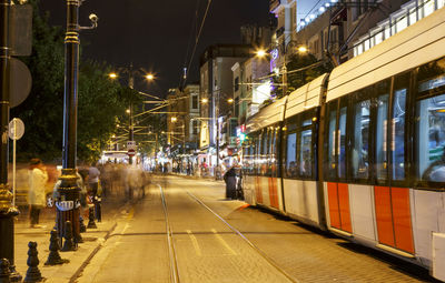 Tram moving on illuminated city street at night