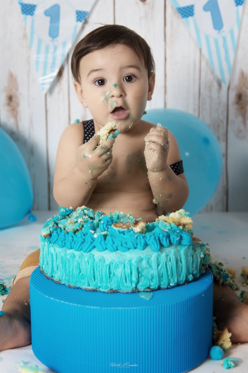 child, one person, cake, real people, childhood, indoors, front view, sweet food, sweet, food and drink, babyhood, innocence, food, dessert, portrait, lifestyles, birthday cake, baby, turquoise colored, temptation, birthday candles
