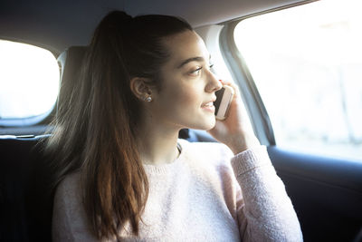 Young woman looking away while sitting in car