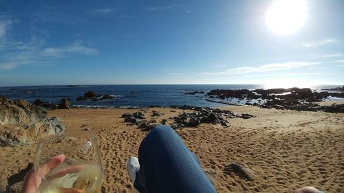 Low section of person on beach against sky