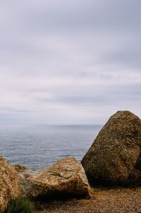 Scenic view of rocks by sea against sky