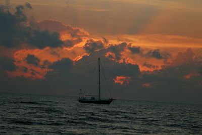 Sailboat sailing on sea against sky during sunset