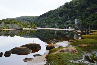 Rocks by lake against sky