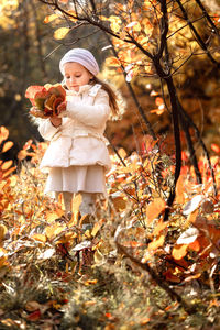 Cute girl holding autumn leaves at park