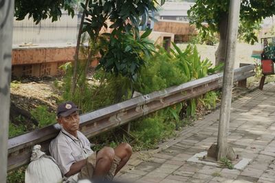 Man sitting on bench by footpath