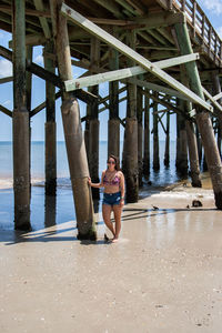 Woman standing against pier at beach