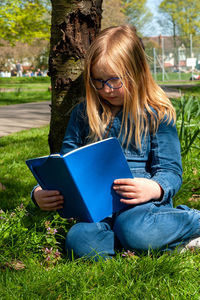 Young woman using laptop while sitting on field