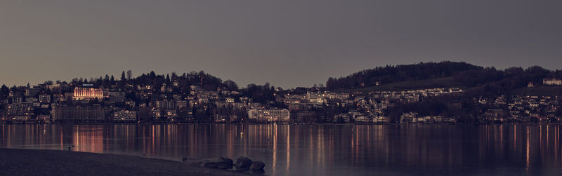 River by buildings against clear sky at dusk