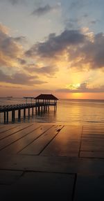 Pier over sea against sky during sunset