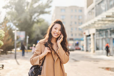 Portrait of young woman standing in city