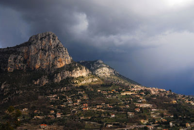 Low angle view of buildings by mountain against sky