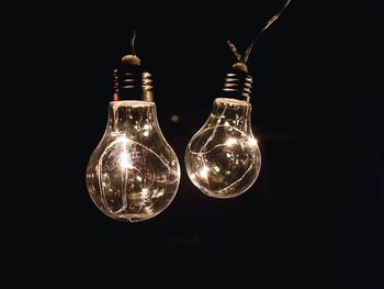 Close-up of illuminated light bulb against black background