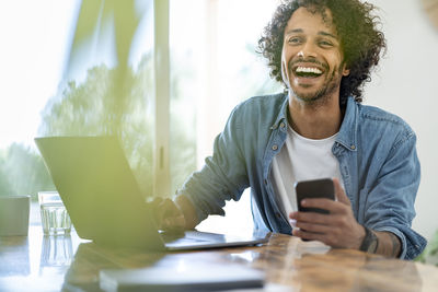 Young man using mobile phone while sitting on table