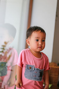 A pregnant woman in a white-green blouse is relaxed in a modern house drinking juice. 