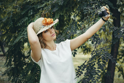 Woman taking selfie through camera against trees