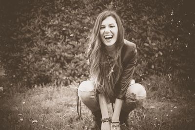 Young woman laughing while crouching on field