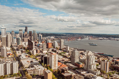 High angle view of buildings and port of seattle and two ferries against clouds and blue sky
