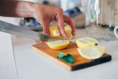 Close-up of hand cutting lemon