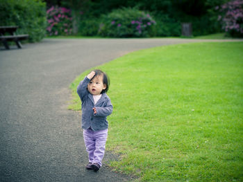 Full length of baby girl with hand in hair walking at park