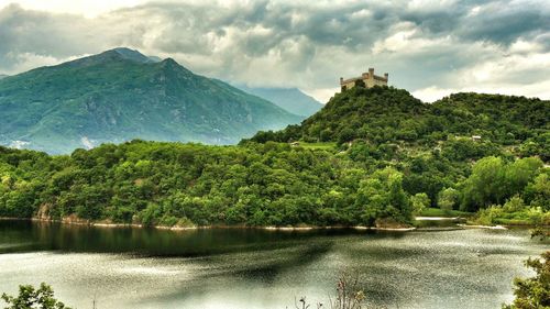 Scenic view of lake and mountains against cloudy sky