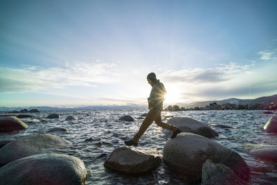 Full length of man standing on rock at beach against sky