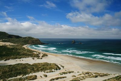 View of calm beach against cloudy sky