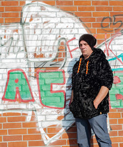 Fashionable mature man standing against graffiti wall