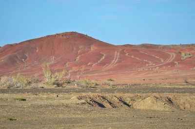 Scenic view of arid landscape against clear blue sky