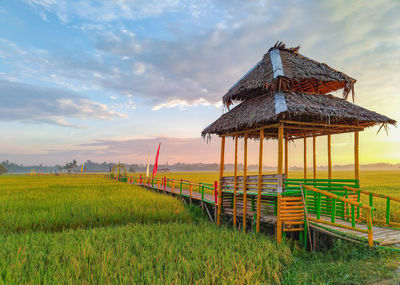 Lifeguard hut on field against sky during sunset