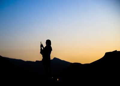 Silhouette man standing on mountain against sky during sunset