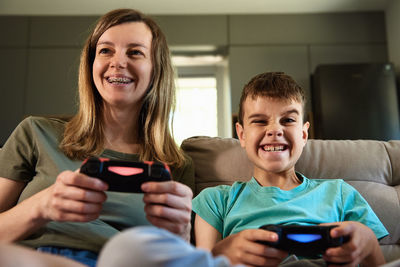 Boy and woman playing video game at home