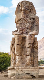  giant statue against cloudy sky. luxor, egypt.