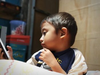 Cute boy using mobile phone while sitting at home