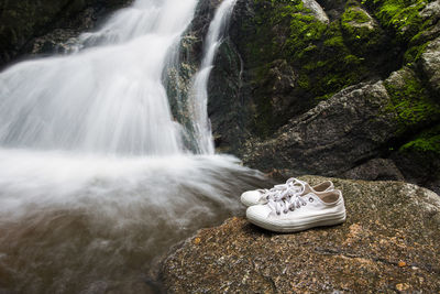 White shoes on rock by waterfall