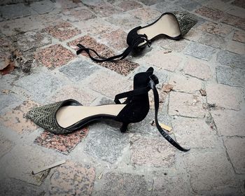 High angle view of high heels on cobbled footpath