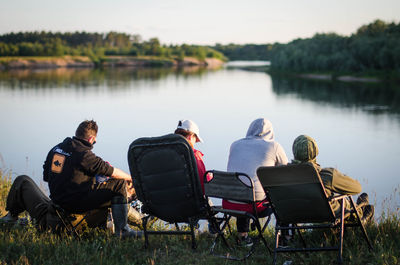 Rear view of people relaxing on lakeshore