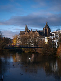 Buildings by river against sky