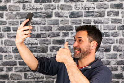 Portrait of man using mobile phone against wall