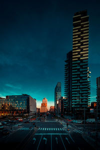 City street by buildings against sky at dusk