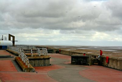 Pier on sea against cloudy sky