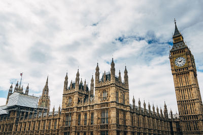 Low angle view of big ben and houses of parliament against cloudy sky