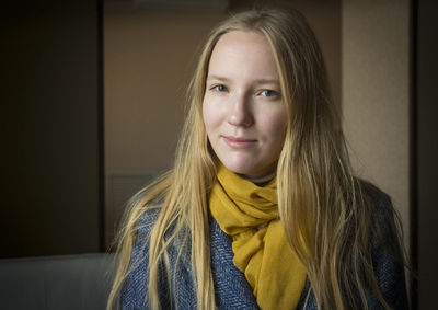 Portrait of beautiful young woman standing against wall during winter