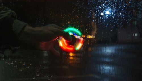 Cropped image of hand holding illuminated spinner