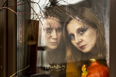 Two female witches look through a spider web ominously out of the window. halloween party.