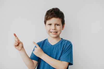 A preschool boy in a blue t-shirt on a light background shows a thumbs up. high quality photo