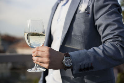 Midsection of businessman holding wine in glass