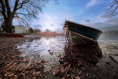 Abandoned boat on beach against sky