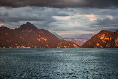 Scenic view of sea and mountains against cloudy sky