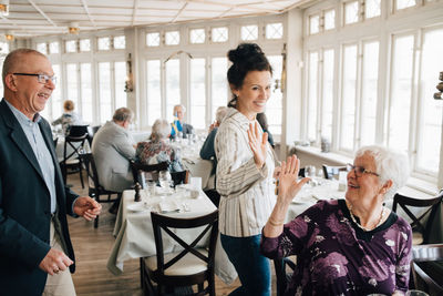 Senior friends giving high-five in restaurant